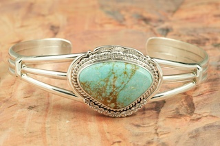 Genuine Number 8 Turquoise set in Sterling Silver Bracelet. The Number 8 mine is located in Eureka County Nevada. Since 1976 there has been no Number 8 Turquoise mined. There is however, an existing stock pile that Mr. Dowell Ward, the last owner of the Number 8 mine, had stocked away for later sorting. The Turquoise is a collector's item--because once the reserve is gone there will be no more material released onto the market. The Gold Mining Company owns the claim to the Number 8 mine and it has been swallowed up by the gold mining operations. This is some of the last Number 8 Turquoise to be had and will be a great addition to your collection. Created by Navajo Artist John Nelson. Signed by the artist. 